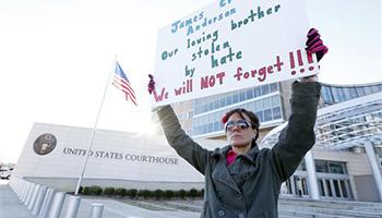 Amelie Hahn, braves cold weather as she holds a poster memorializing the 2011 rundown death of James Craig Anderson in front of the federal courthouse in Jackson, Miss., Wednesday, Jan. 7, 2015. Two of the men charged in the series of 2011 racial beatings that resulted in Anderson's death attended change-of-plea hearing.